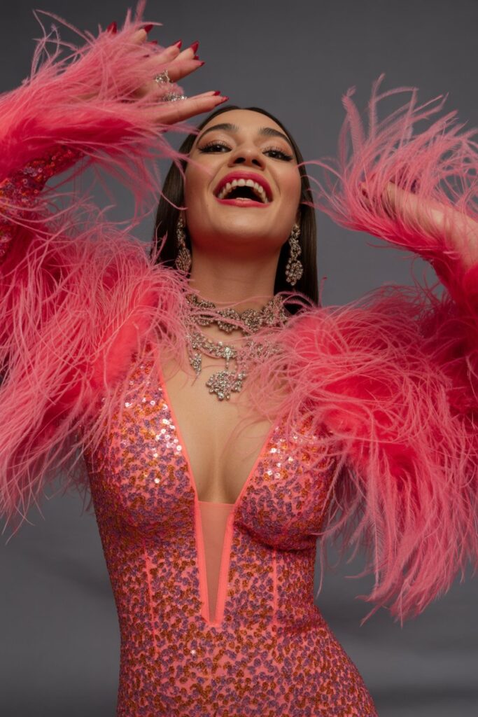 A woman in a bold, embellished, maximalist dress, exuding confidence and joy.